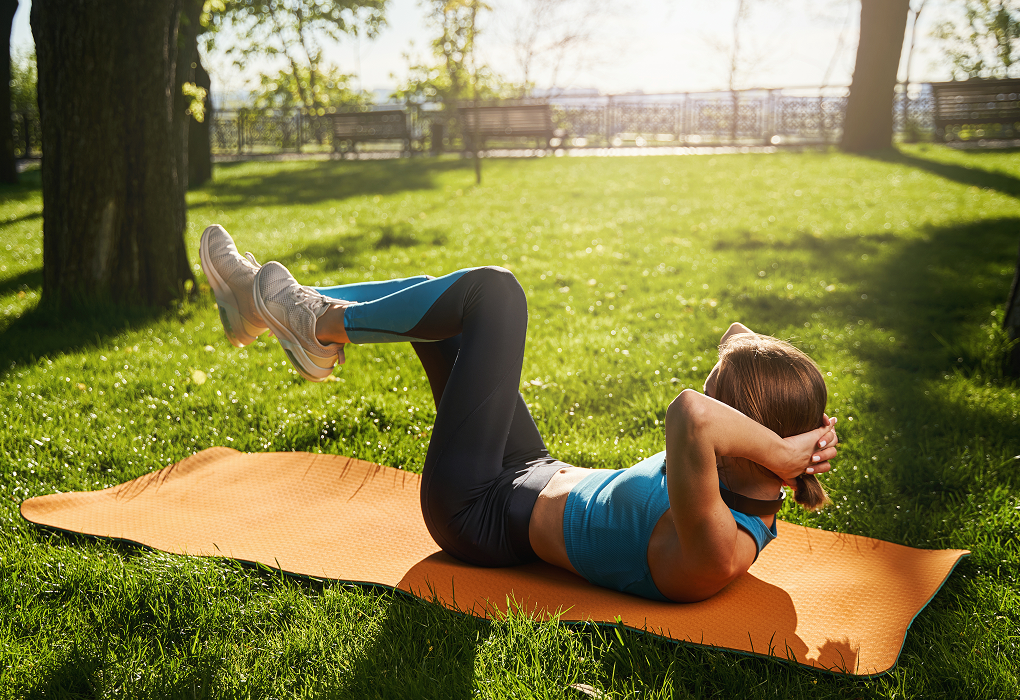lady in park on yoga mat exercising