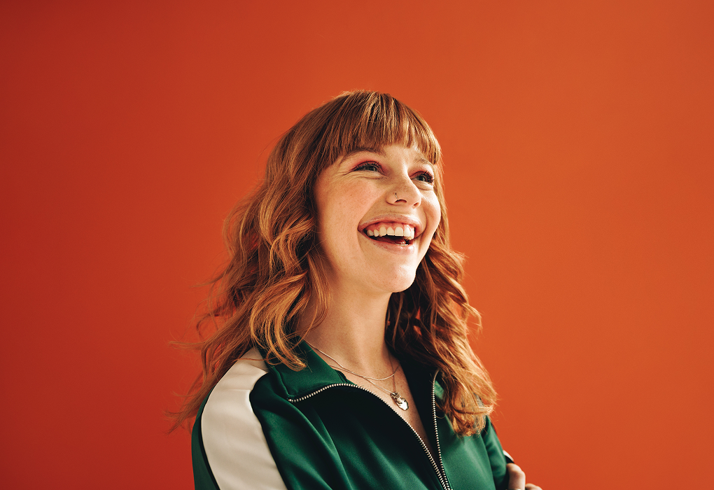 lady smiling against an orang backdrop