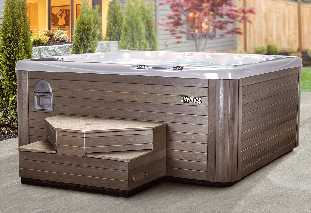 beachcomber hot tub in backyard with bushes and flowers