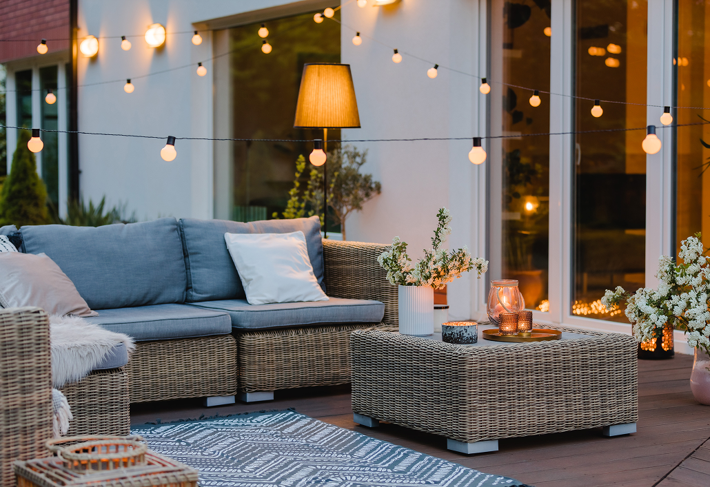 patio next to house with wicker furniture and ourdoor lights