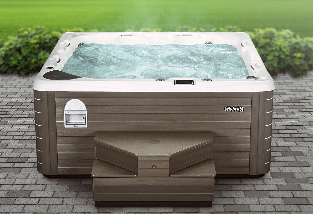hybrid4 hot tub in backyard on bricks with grass and bushes