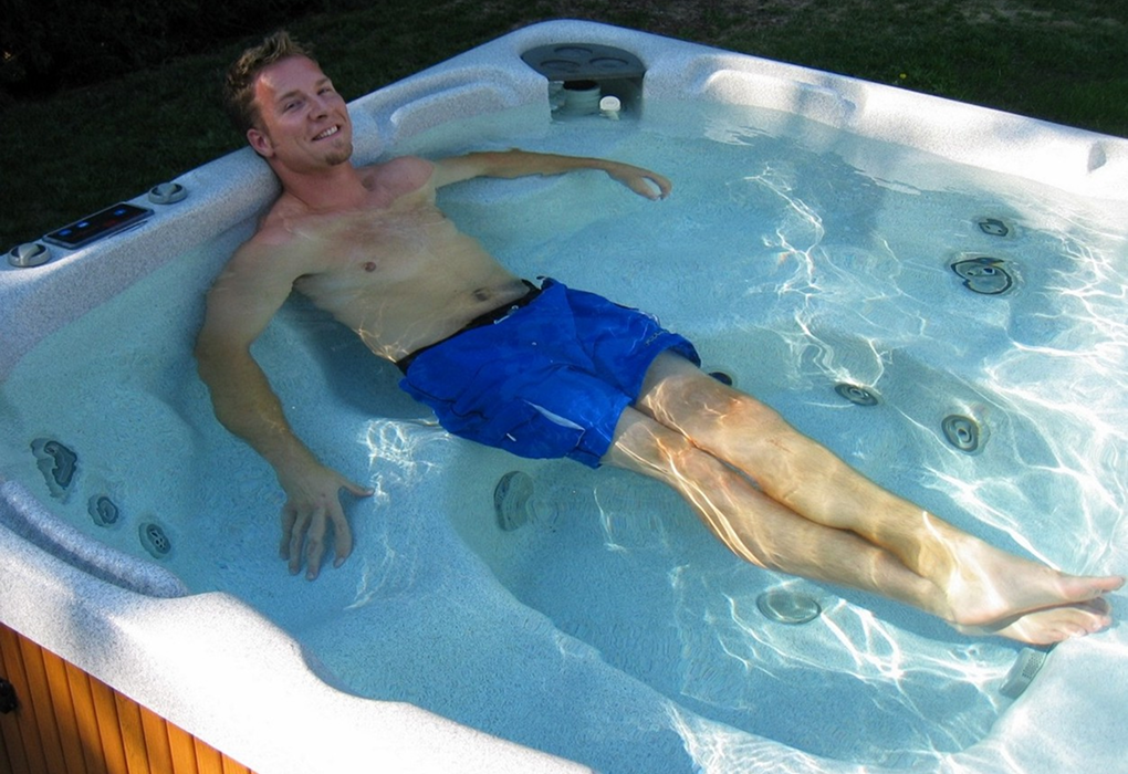man laying down lounging in a beachcomber hot tub