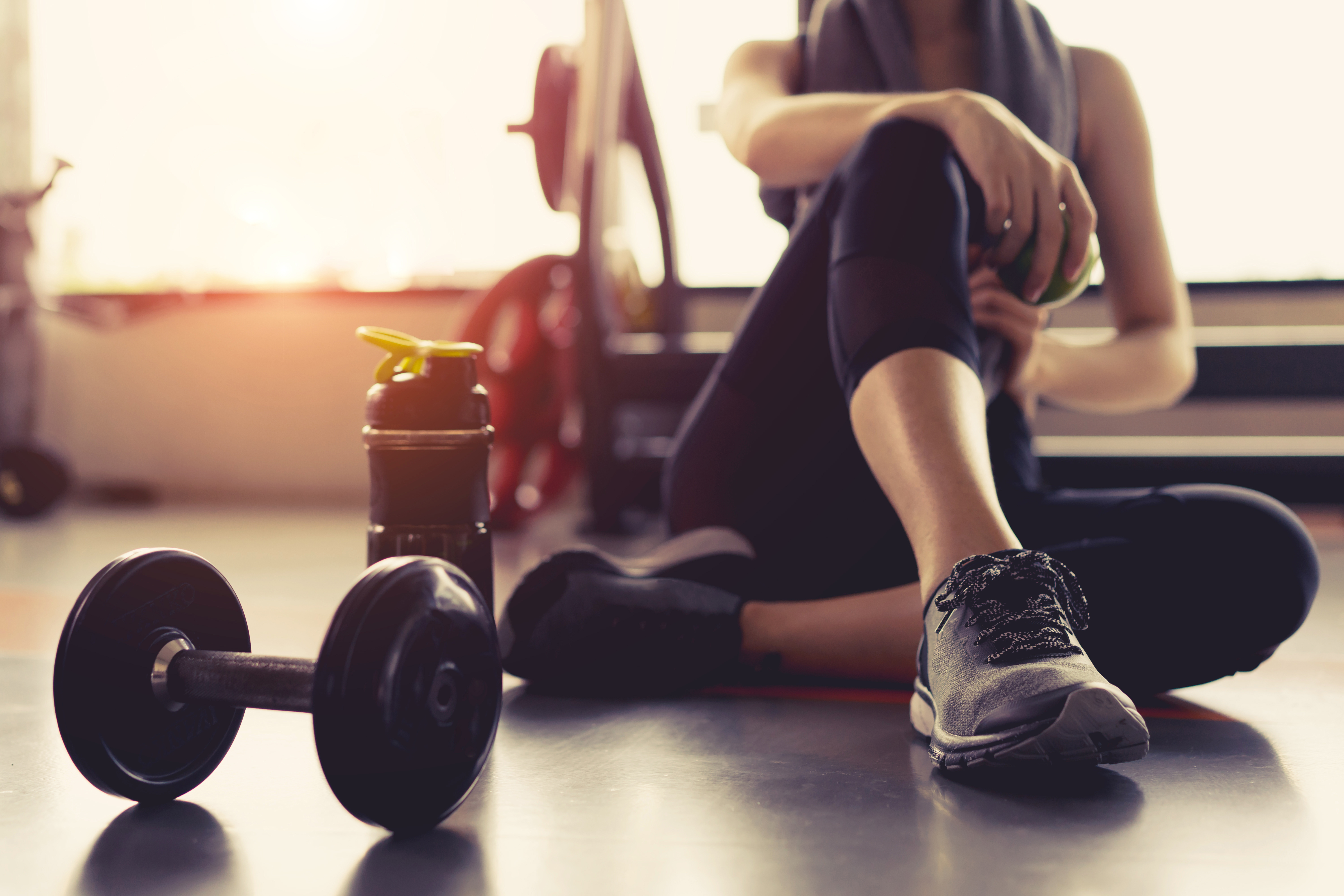 person sitting on floor with weights and other exercise equipment