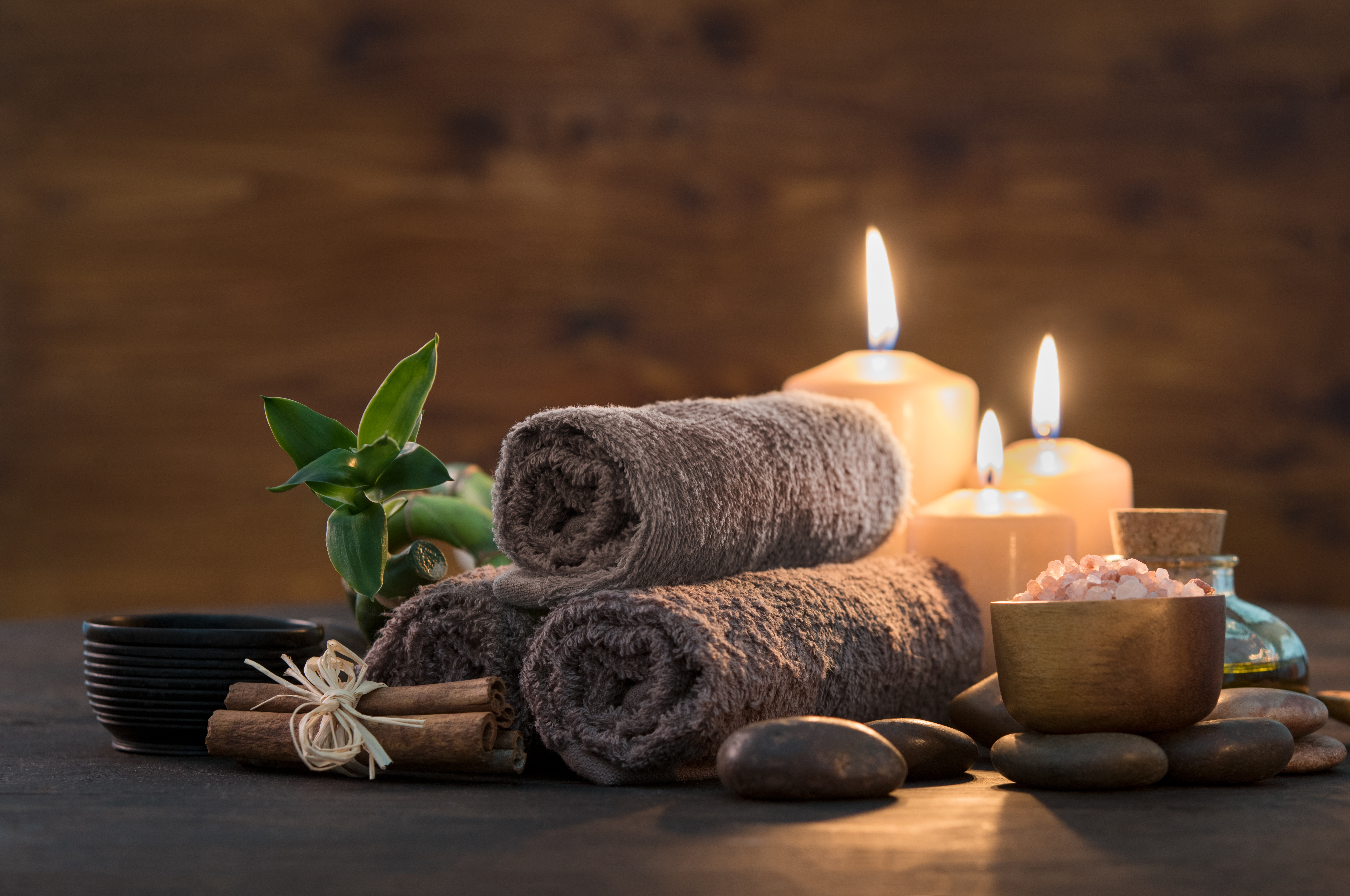 rolled up towels in pyramid shape, green plant, rolled up twigs, black bowl, stones, gold bowl with rocks, 3 lit candles