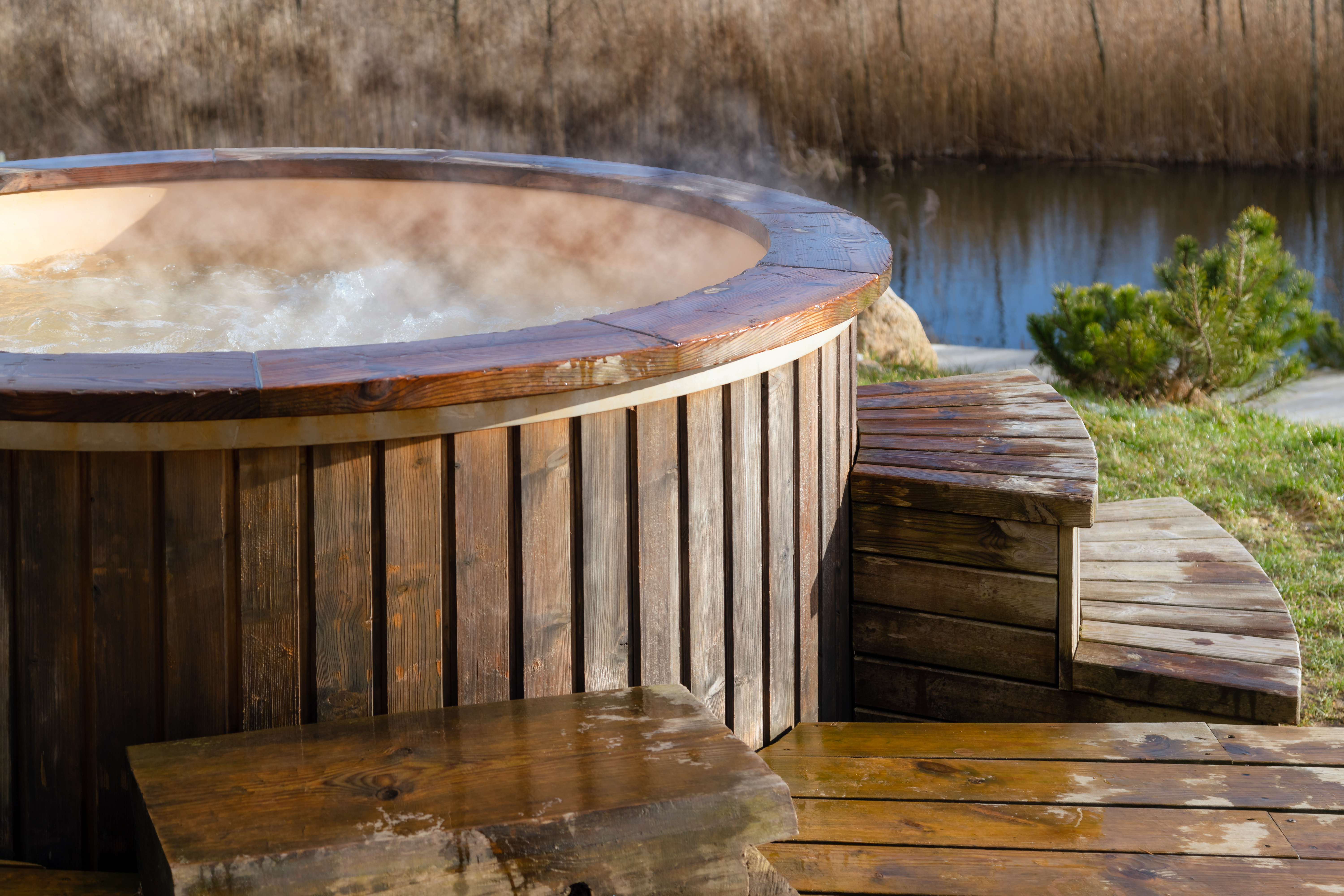 How water swirling in wooden hot tub outside in nature. Enjoying hot steaming pool on a sunny day, private spa treatment. 