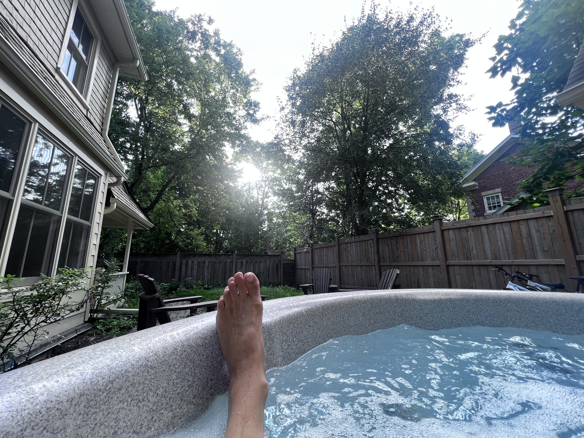 hot tub in backyard with someone lying in it resting their leg on the side