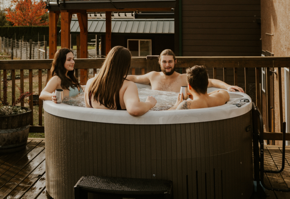4 people sitting in beachcomber 320 leep hot tub on a deck 