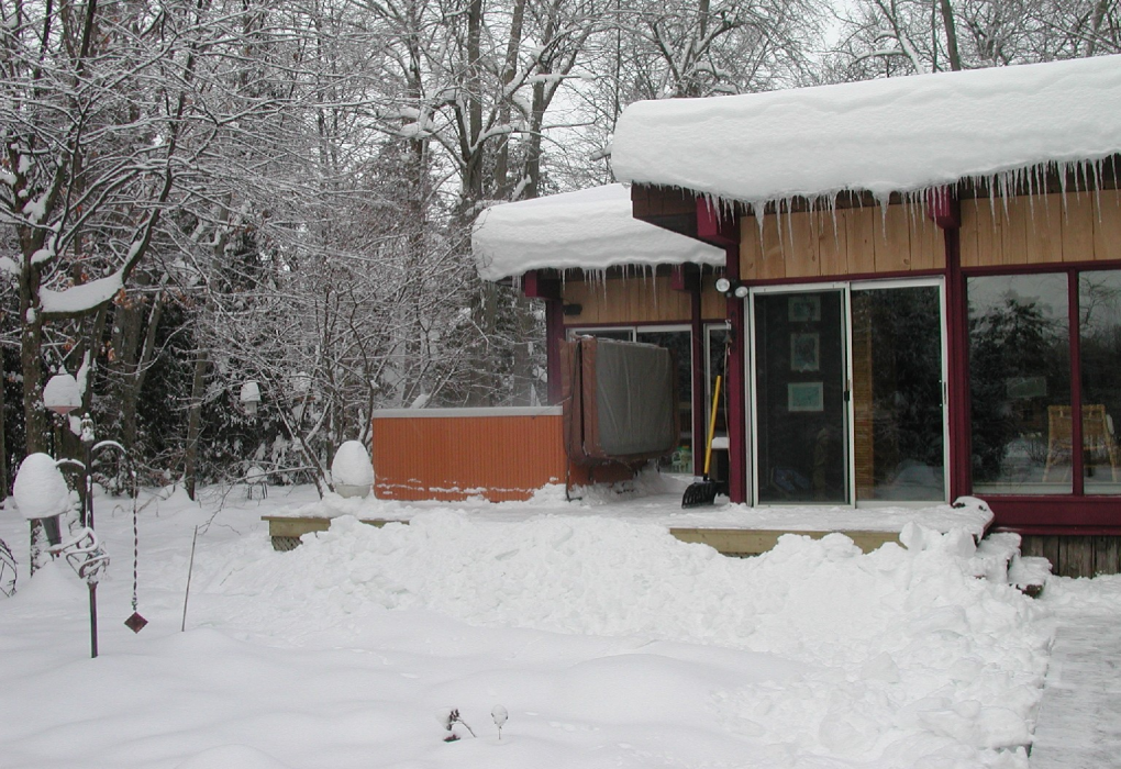 snowy backyard with hot tub next to house