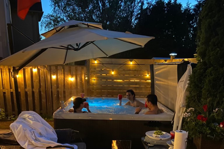 three people in beachcomber hot tub enjoying drinks and laughing