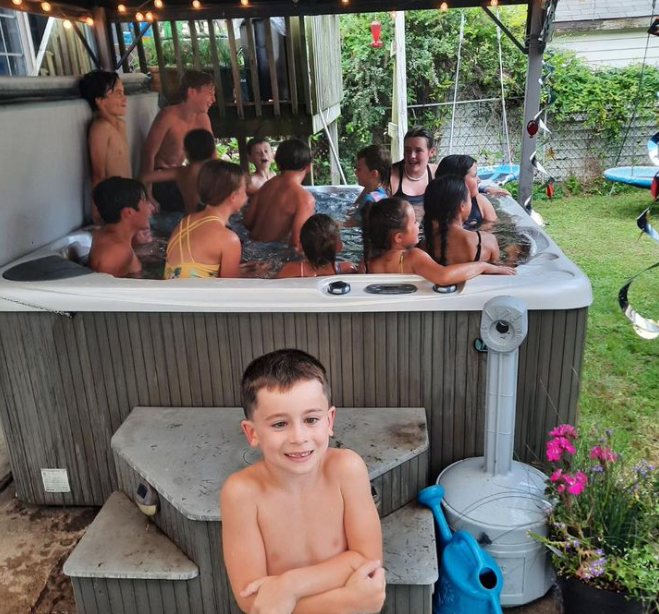 beachcomber hot tub filled with children with one child standing in front of the camera smiling